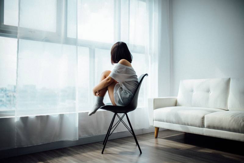 Une femme inquiète qui regarde par la fenêtre