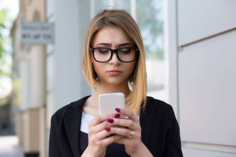 Une fille malheureuse regarde son téléphone à l'extérieur