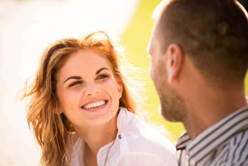Une jeune femme souriante regarde les yeux de son homme