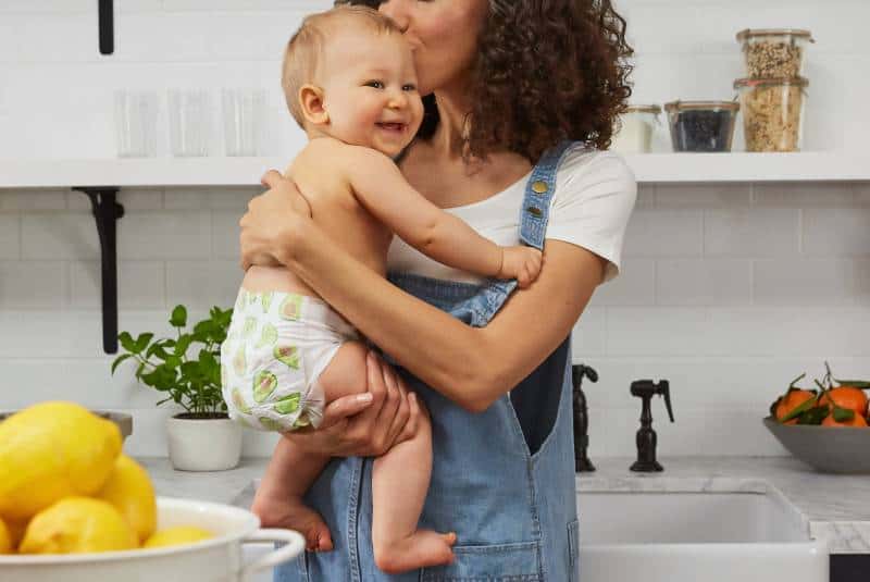 Une mère qui tient son bébé dans ses bras à la cuisine
