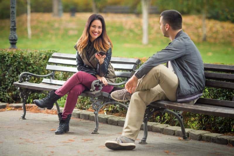 couple assis sur un banc dans un parc et discutant