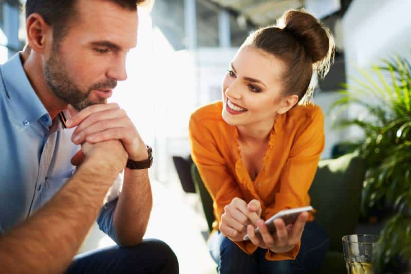 couple heureux assis au café et regardant le téléphone