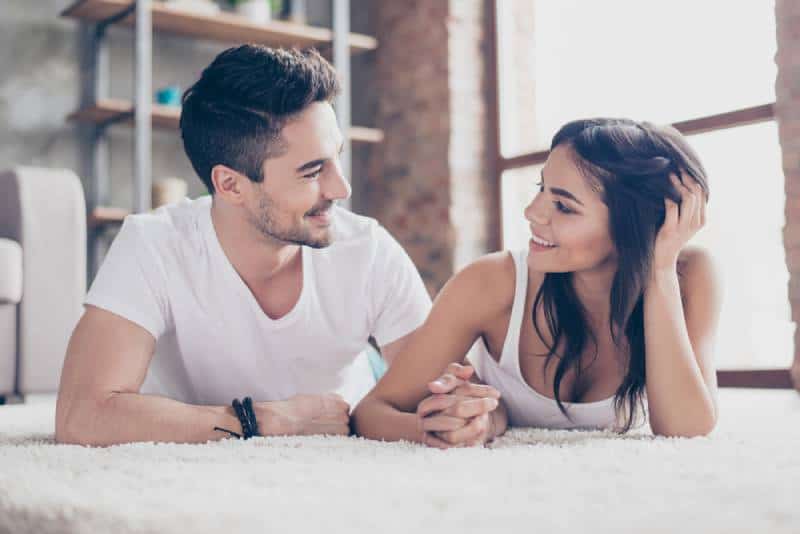 couple romantique allongé sur le tapis douillet de la maison
