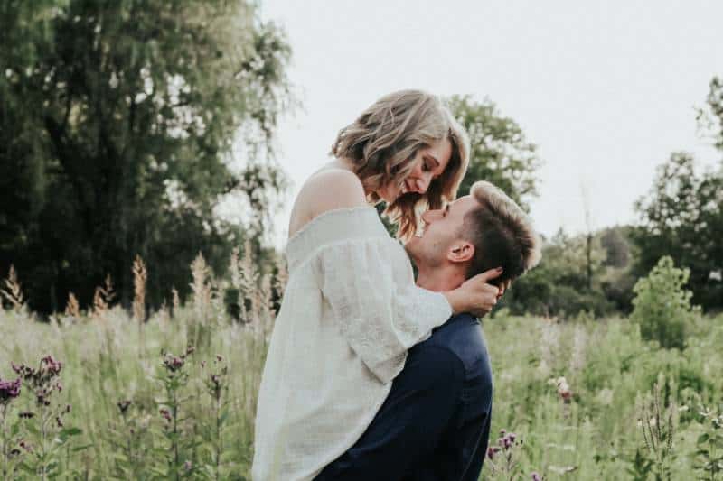 couple s'embrassant dans un champ d'herbe
