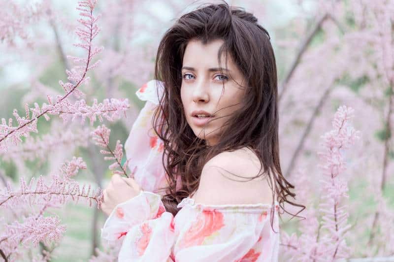 femme debout près d'un champ de feuilles roses