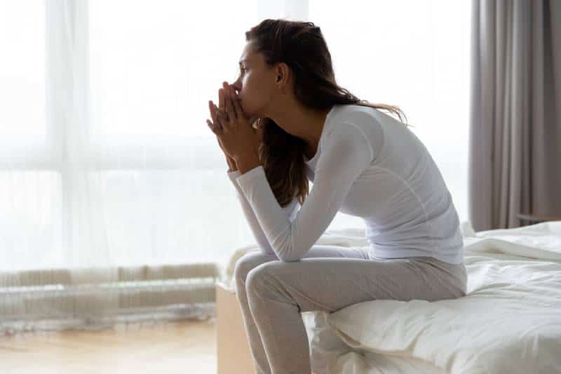 femme inquiète, assise sur son lit dans la chambre