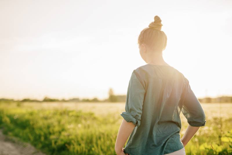 femme marchant près d'un champ d'herbe