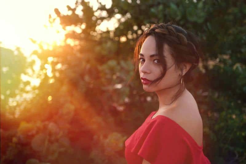 femme portant une cime rouge près d'un arbre à feuilles vertes
