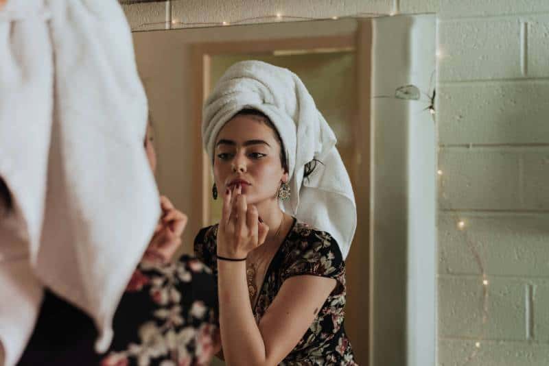 femme se maquillant devant le miroir