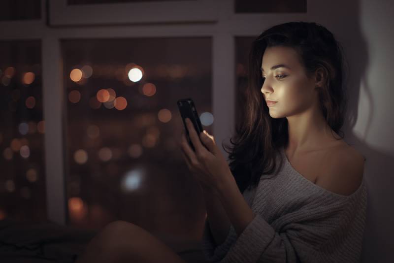 femme solitaire, taper sur son téléphone la nuit