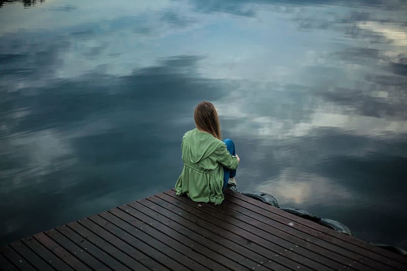 femme triste assise au bord du lac