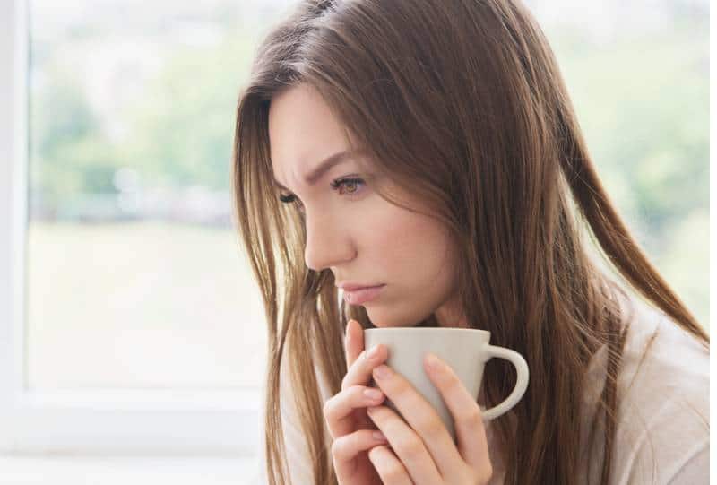 femme triste tenant une tasse et pensant à la maison