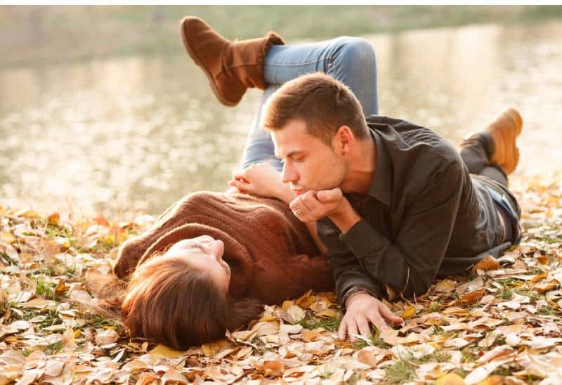 jeune homme et jeune femme allongés près d'un lac en train de parler