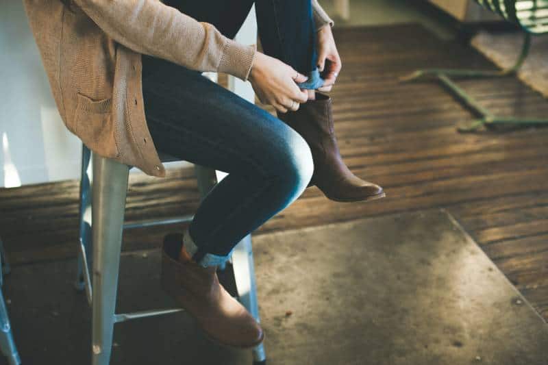 personne en manteau gris assise sur un tabouret à l'intérieur de la pièce
