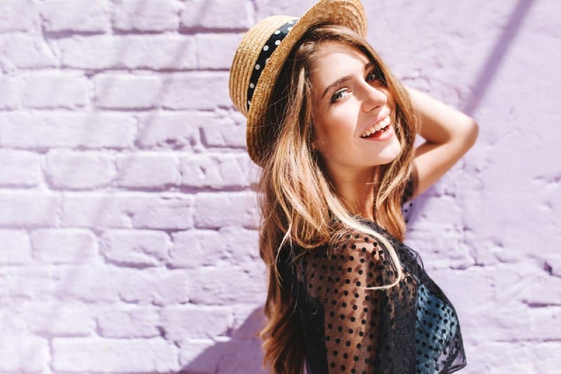 portrait d'une femme souriante à l'extérieur sur le soleil devant le mur