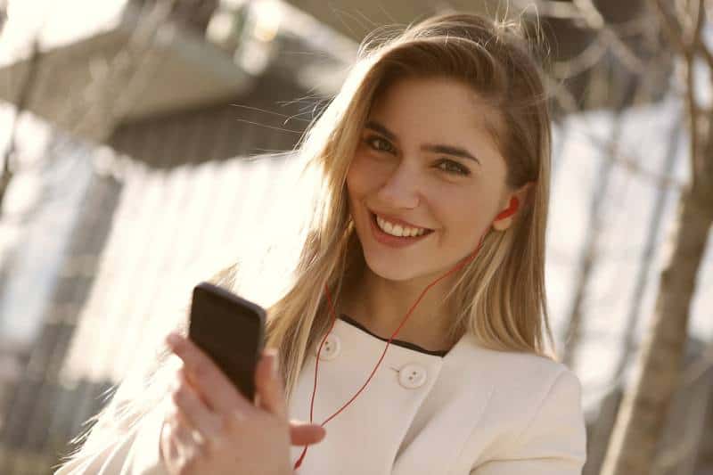 portrait d'une jeune fille souriante qui tape sur son téléphone