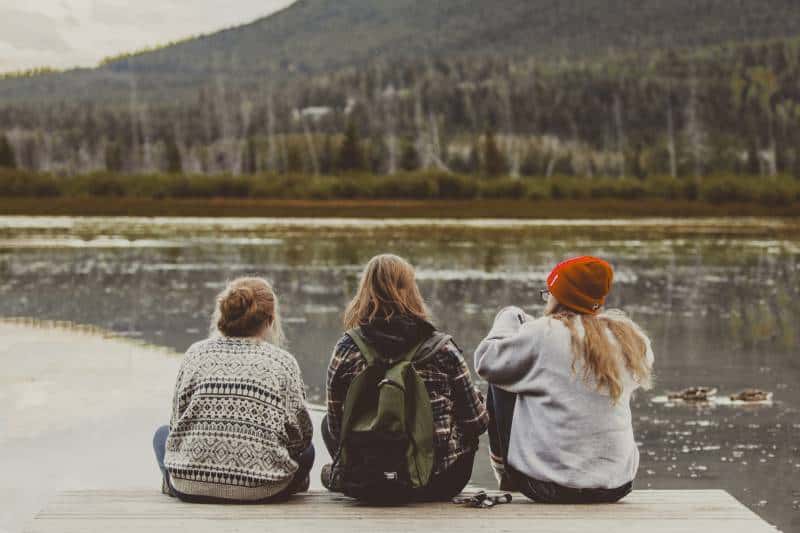 trois amies assises au bord du lac