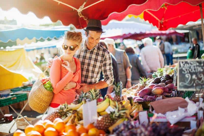 un couple qui achète des fruits et légumes sur un marché