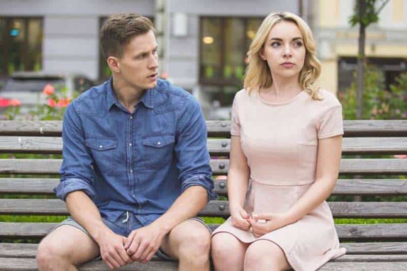 un homme est assis avec une femme sur un banc et lui explique quelque chose