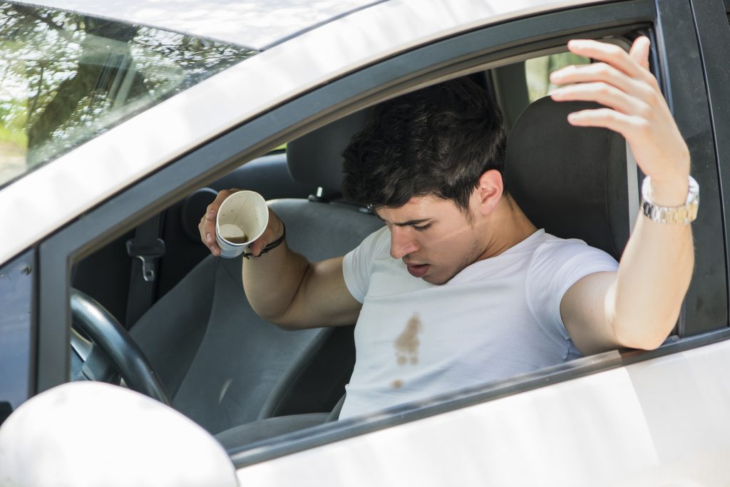 un homme renversé du café dans une voiture