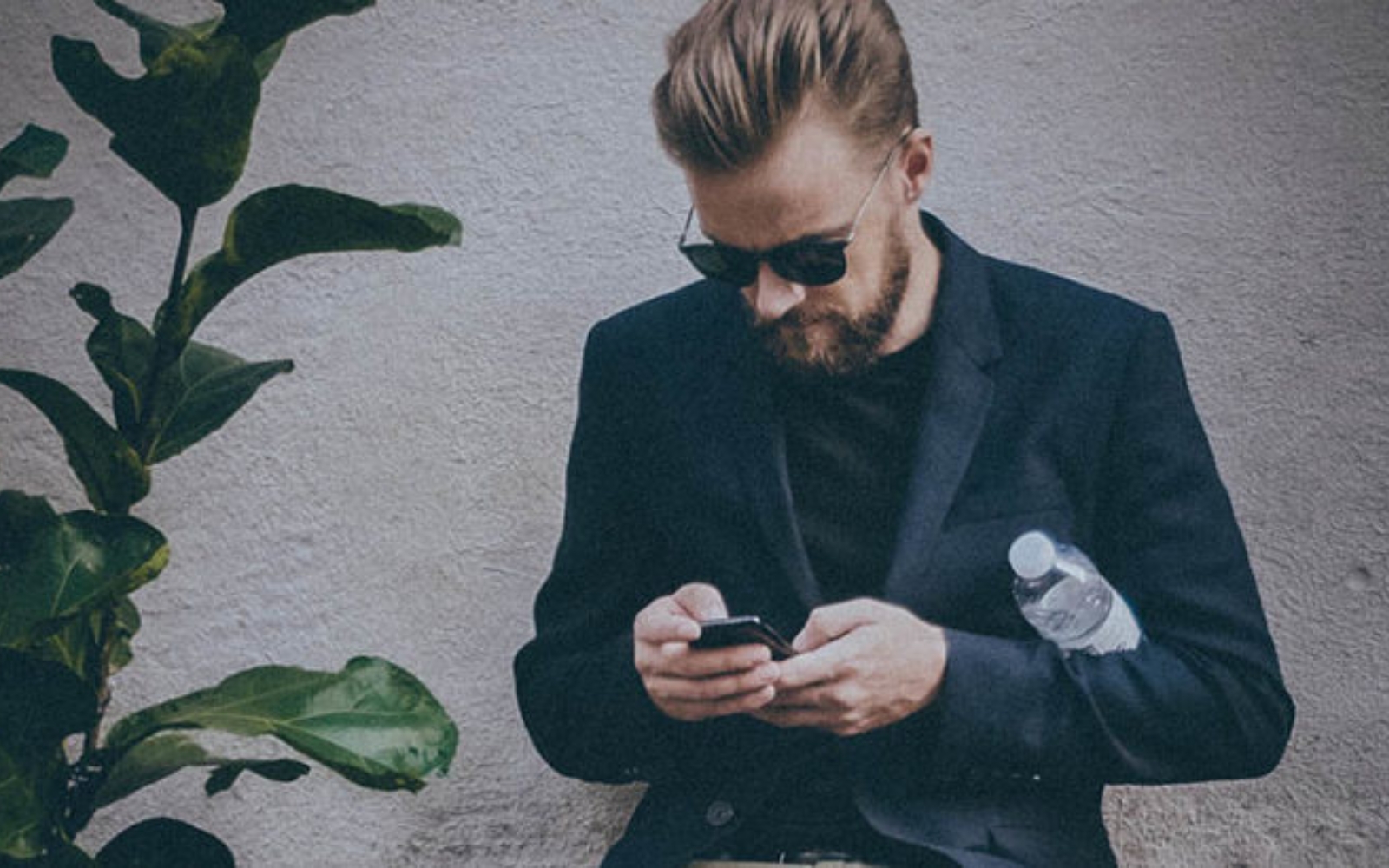 homme en costume tapant sur son telephone