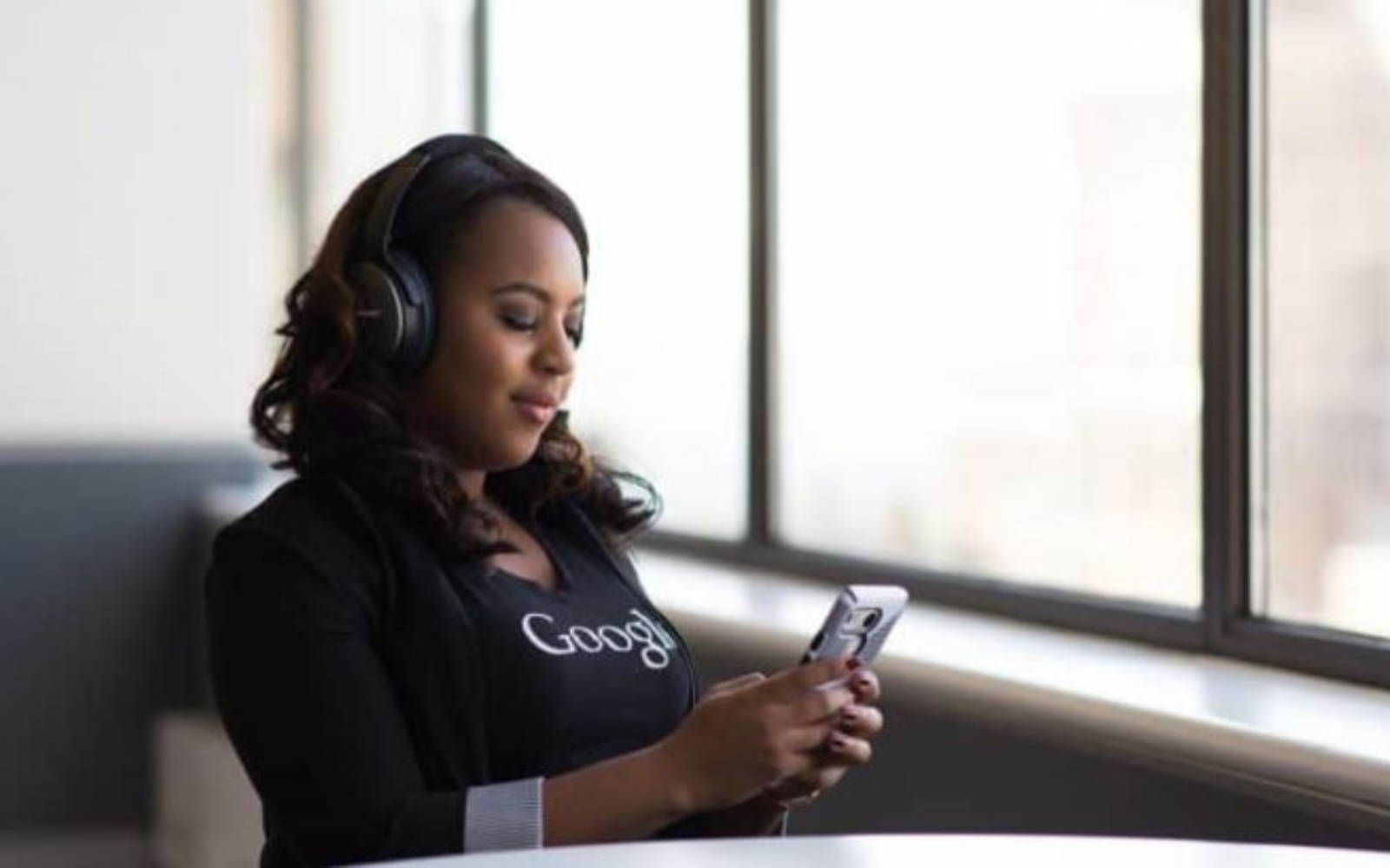 une femme avec un telephone a la main et des ecouteurs sur les oreilles