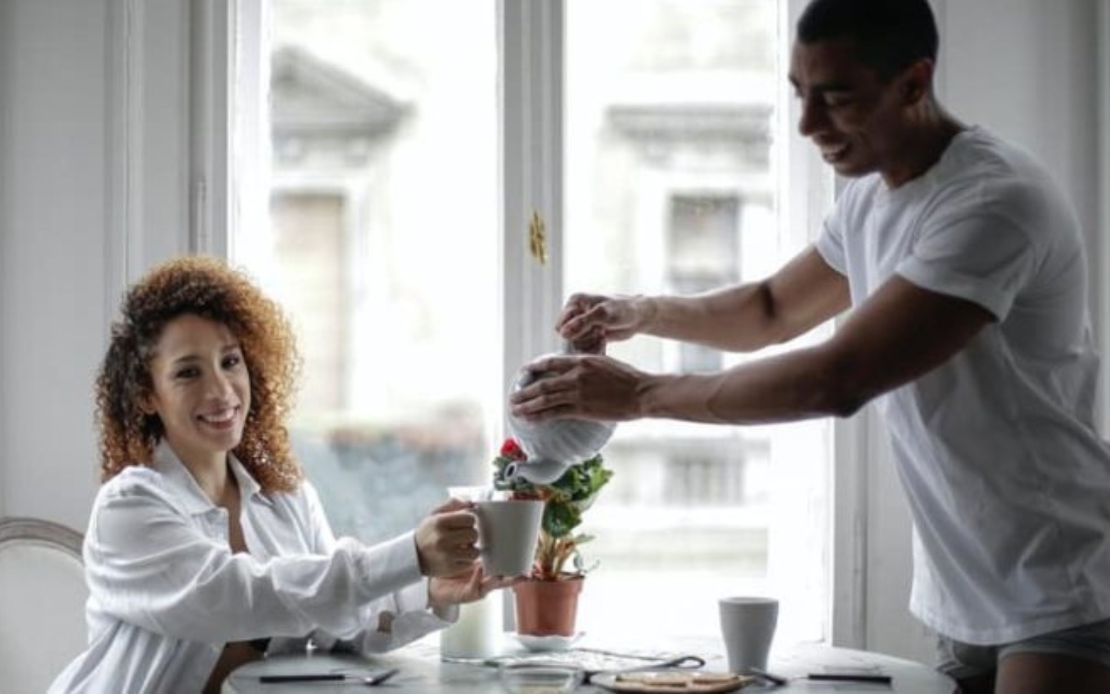 un homme et une femme sassoient a une table et boivent du cafe