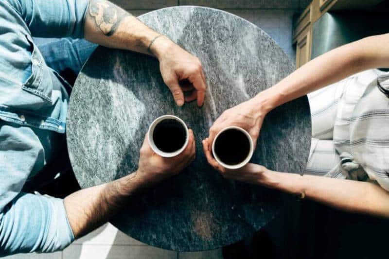 Couple assis dans un café tenant une tasse