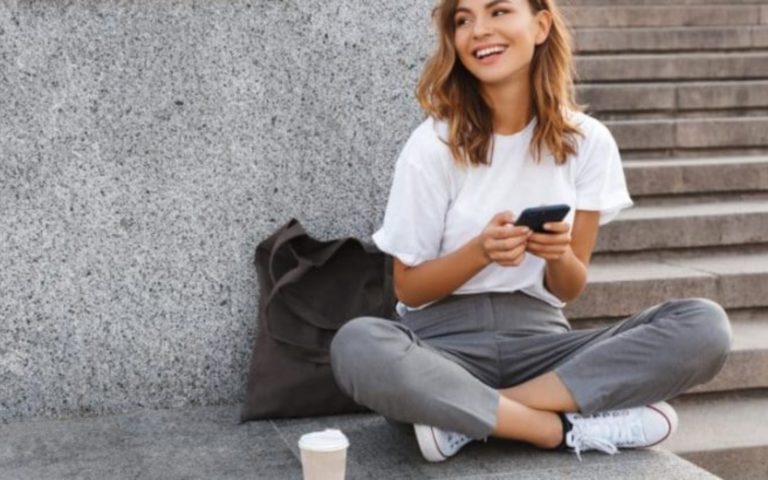 une femme assise sur le sol avec un telephone a la main