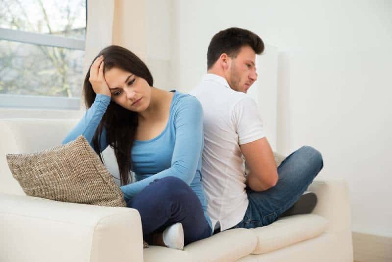 Un couple attentionné assis dos à dos sur le canapé