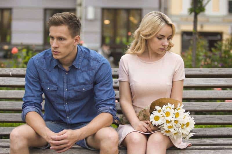 Un couple malheureux s'assoit après la dispute, une fille avec des fleurs