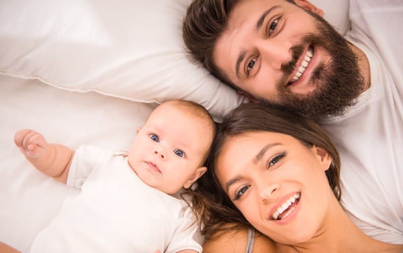 jeune couple heureux avec bébé couché dans son lit