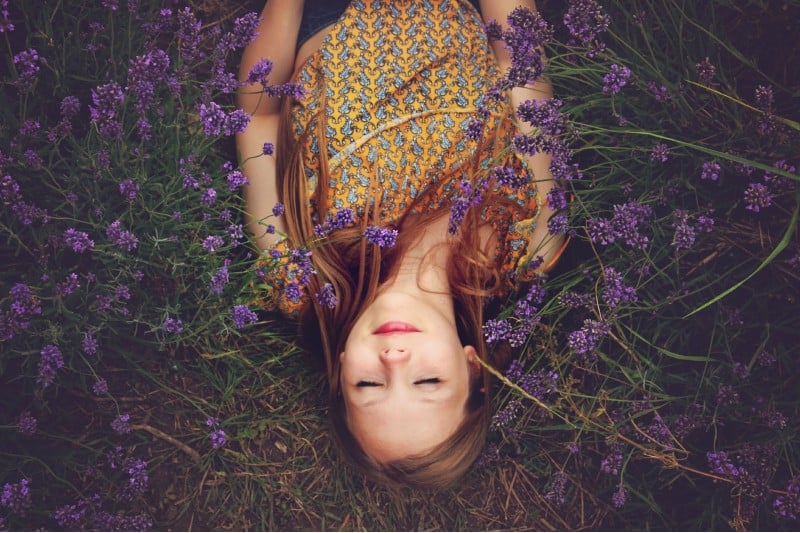 une jeune femme allongée sur un champ de fleurs violettes