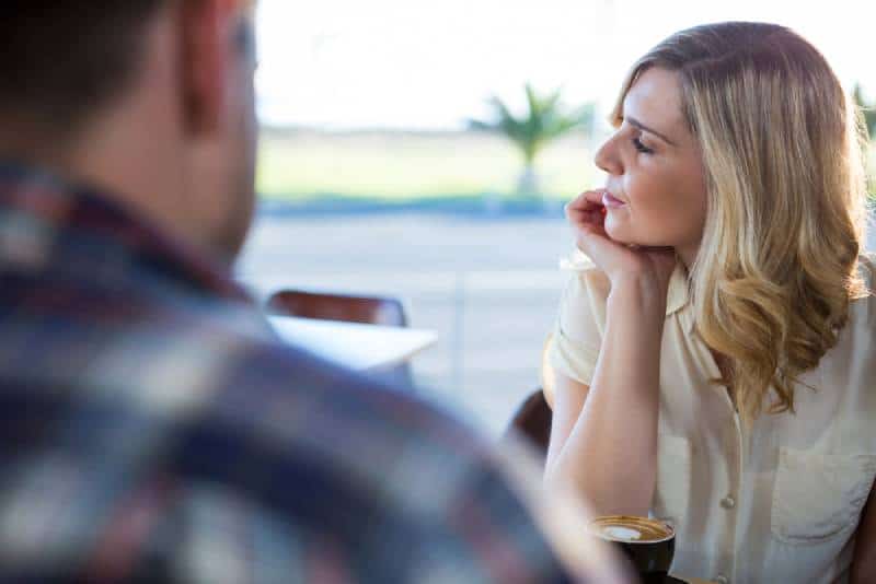 femme bouleversée regardant au loin alors qu'elle est assise avec un homme