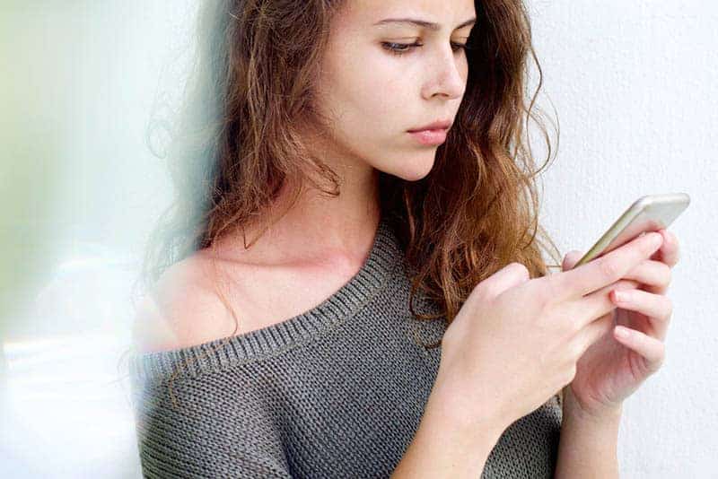 femme pensive tapant sur son téléphone