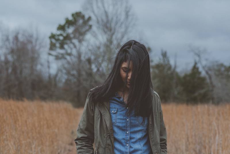 femme portant un cardigan gris entouré d'herbe