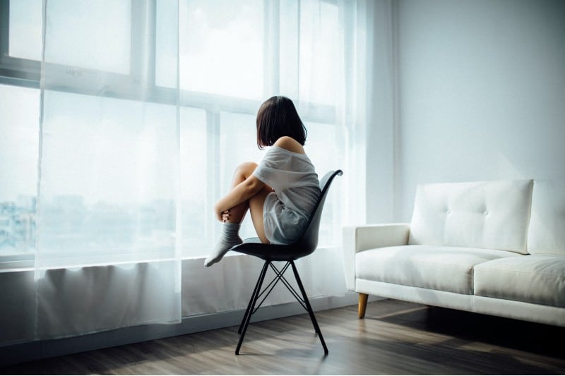 femme solitaire, assis sur une chaise près de la fenêtre dans une pièce vide