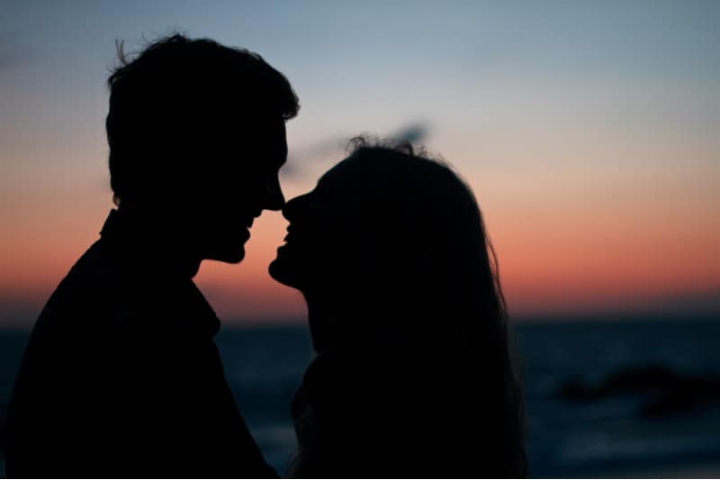 heureux couple baisers à l'extérieur au coucher du soleil