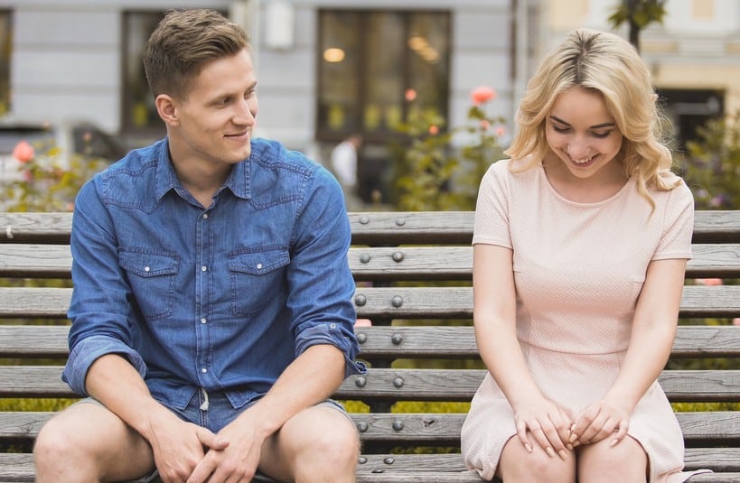 homme assis près de femme blonde sur un banc