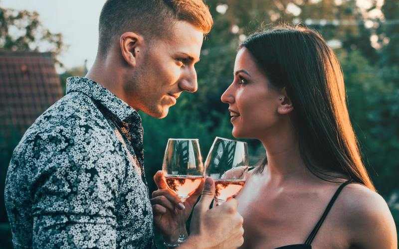 homme et femme face à face avec des verres à vin