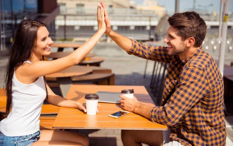 homme et femme assise à une table donnant high five