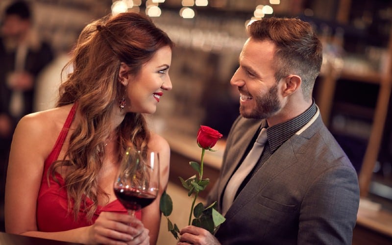 Homme souriant donnant rose a une heureuse belle femme