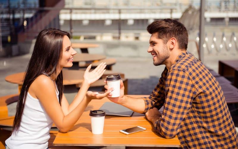 jeune heureux couple assis à une table et parlant