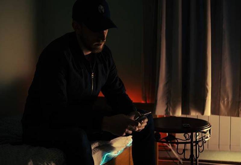 photo sombre d'un homme tapant sur son téléphone à la maison