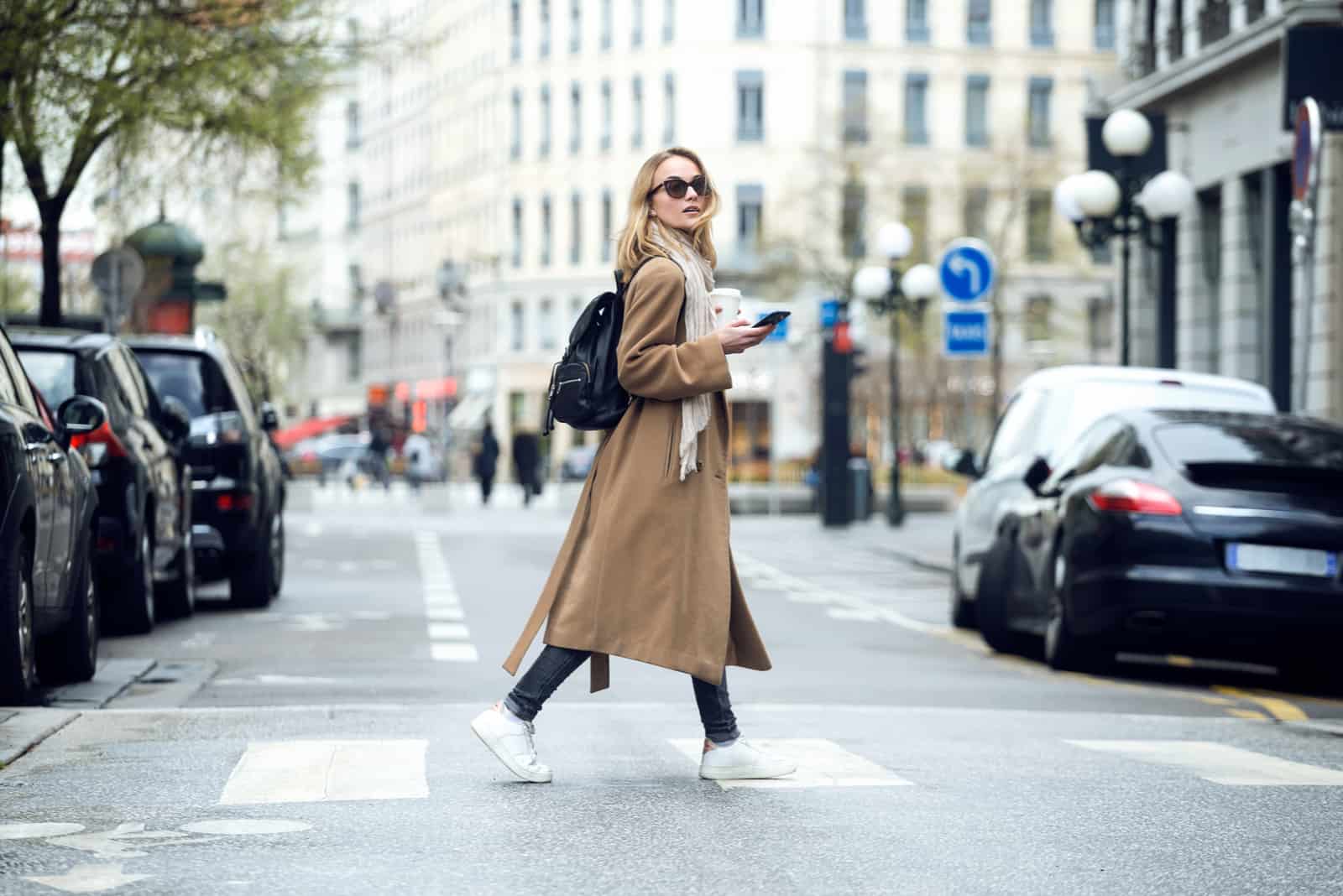 une femme en manteau marron marche dans la rue