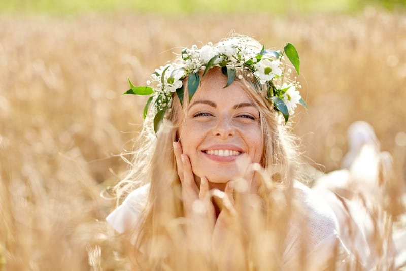 une femme heureuse allongée sur un champ portant une couronne de fleurs