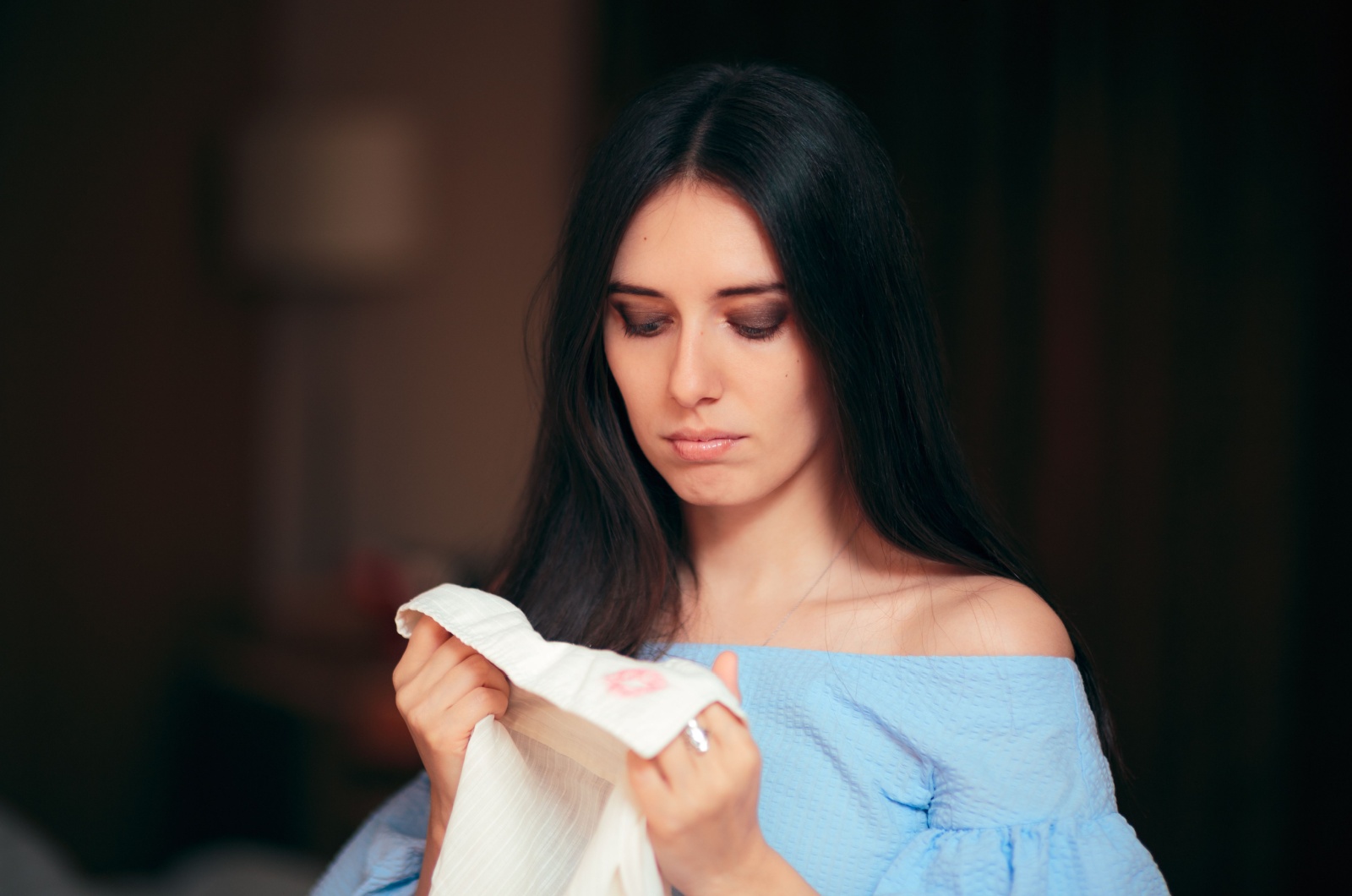 femme tenant une chemise avec une tache de rouge a levres