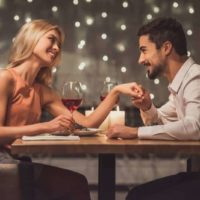 Un beau jeune couple se regarde et sourit pendant leur rendez-vous dans un restaurant