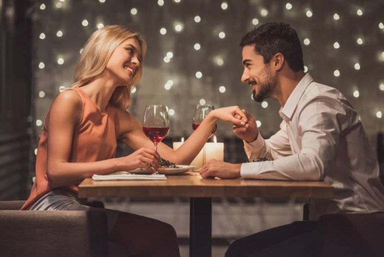 Un beau jeune couple se regarde et sourit pendant leur rendez-vous dans un restaurant