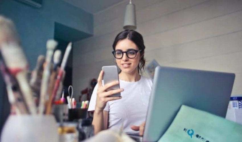 femme assise a une table et en appuyant sur un telephone